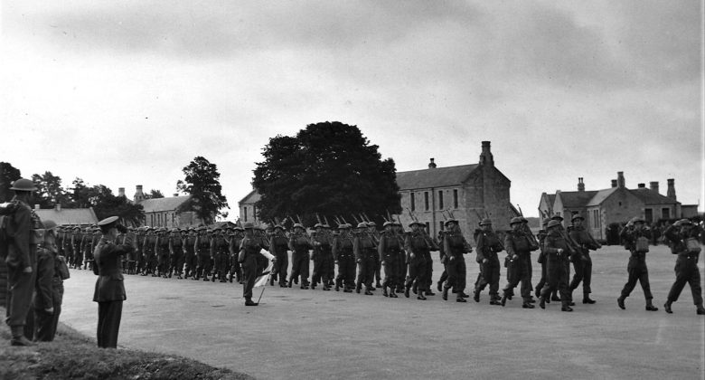 Black and white photograph of troops marching in a line outside Bodmin Barracks.